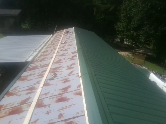 Old rusted panels beside newly installed green metal roofing in Diamond