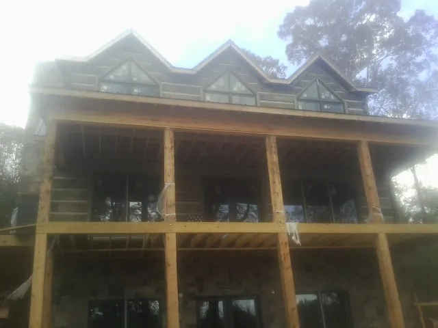 Dormers and porch framing on a large log home under construction — Roof Coating work by our crew in Diamond