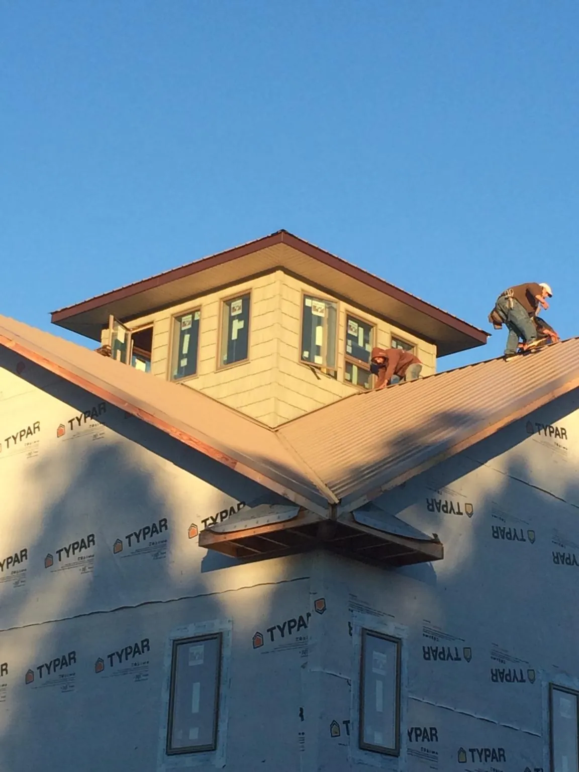 Roofers working around a rooftop cupola on a new metal roof at sunset — Roof Waterproofing in Diamond by Roofing Brothers